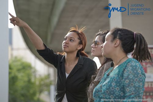 drei junge Frauen zeigen auf etwas außerhalb des Bildes. 