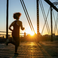 Ein Mensch auf einer Brücke vor dem Sonnenuntergang
