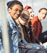 junge Menschen sitzen nebeneinander und schauen in die Kamera