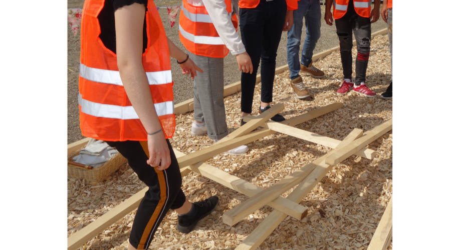 Junge Menschen mit Warnwesten und Holzteilen