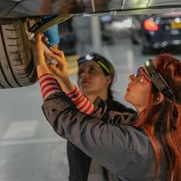 Zwei junge Menschen arbeiten von unten an einem Auto