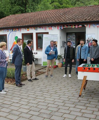 Viele Menschen stehen in einem Hof und es wird eine Rede gehalten. 