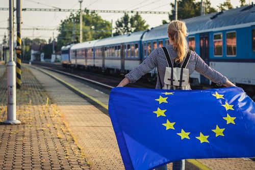Ein Mensch mit einer Europafahne an einem Bahnhof