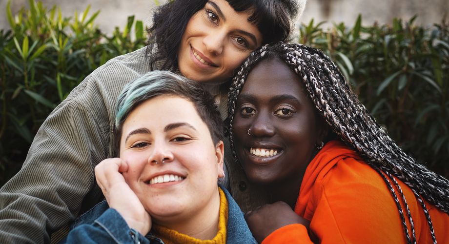 drei junge Frauen schauen fröhlich in die Kamera