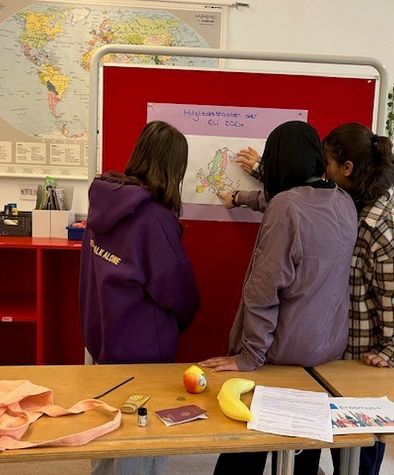 3 Frauen schauen sich etwas an.